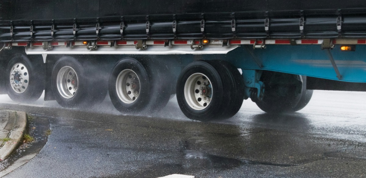 Working trailer wheels moving through rain on a freight route